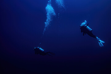 Two Scuba divers swimming in deep blue