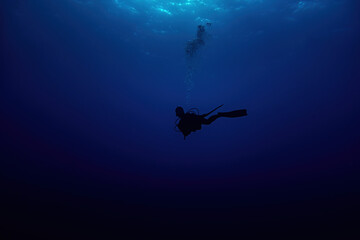 Woman scuba diver silhouette swimming in deep blue