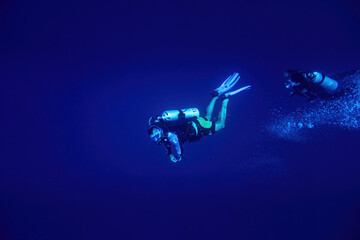 Two scuba divers swimming in deep blue