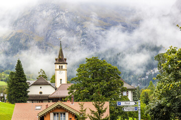 The reformed church in the famous Swiss recreational village Grindelwald with the foggy mountain at...