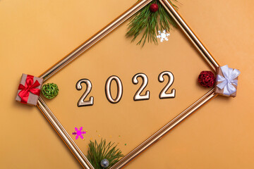 New Year's layout on a beige background: Christmas balls, branches of a Christmas tree, a gift box and a gold frame, a mockup of a postcard, an invitation