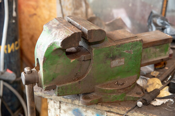 Old iron vise on the workbench. Violation of safety regulations. A dangerous tool.