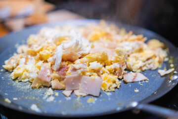Scrambled eggs with chopped turkey ham on a round griddle