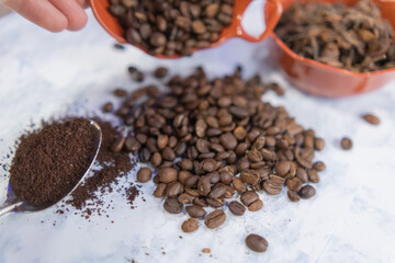 Spoonful of coffee and pots of coffee beans and anise seeds on white surface