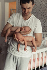 Father holding sleeping newborn twins on his arms. Twins sleeping like coalas. Selective focus....