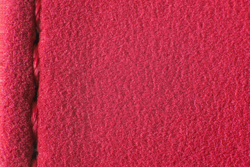 Part of the surface of a red fabric with a seam.