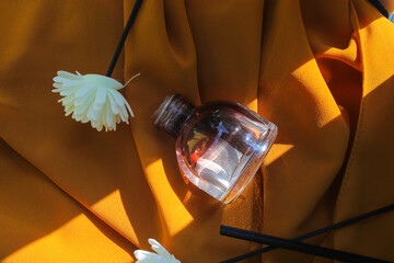 50 ml Perfume bottle with white flower on textured orange fabric background. Perfume bottle stock photo