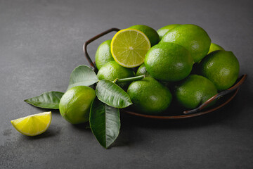 Fresh green limes with leaves on gray stone table