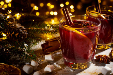 Mulled wine with spices and fruits on wooden table