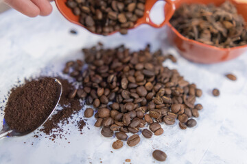 Spoonful of coffee and pots of coffee beans and anise seeds on white surface