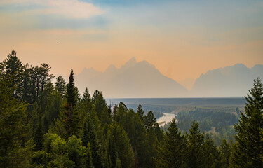 Grand Teton Mountain Range obscured by wild fire smoke with the Snake River seen in the foreground 
