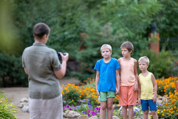 Mom takes pictures of children in park against background of flowers