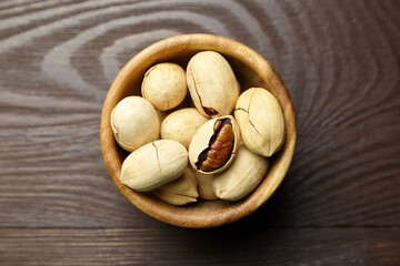 Pecan nuts in bowl on wooden table top view