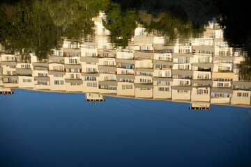 The building is reflected in the water. The surface of the lake in the park. The white building is reflected as in a mirror.