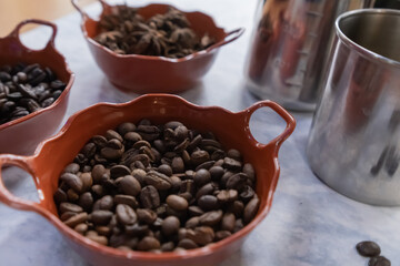 Fototapeta premium Three pots of roasted coffee beans and star anise seeds on white surface