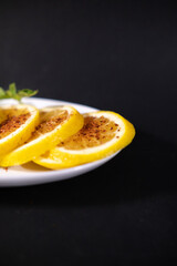 Plate of orange slices with chili powder on black surface