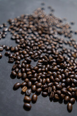 Pile of roasted coffee beans on dark gray surface