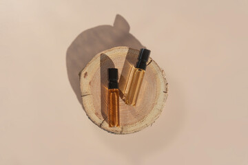 Two glass perfume samples on a wooden tree tray lying on a beige background. Luxury and natural...