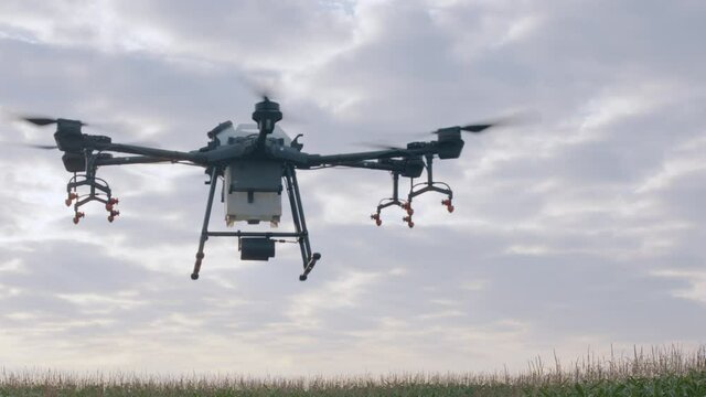 CU view of a huge intelligent agriculture drone with spray nozzles flying against sky at dawn