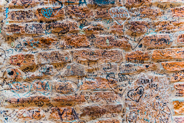 Verona, Italy - September 20, 2021: Stone wall next to Juliet's house, in Verona, where lovers leave their signatures and messages of love. - obrazy, fototapety, plakaty