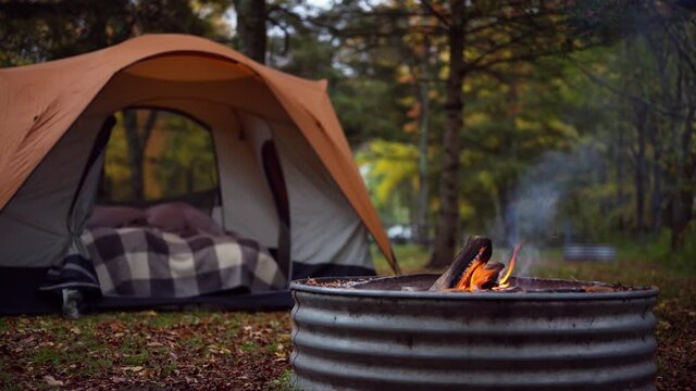 closeup of campfire with tent in background on fall camping trip