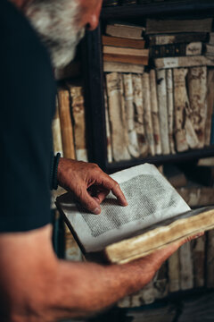 Senior man hands holding an old book in a library