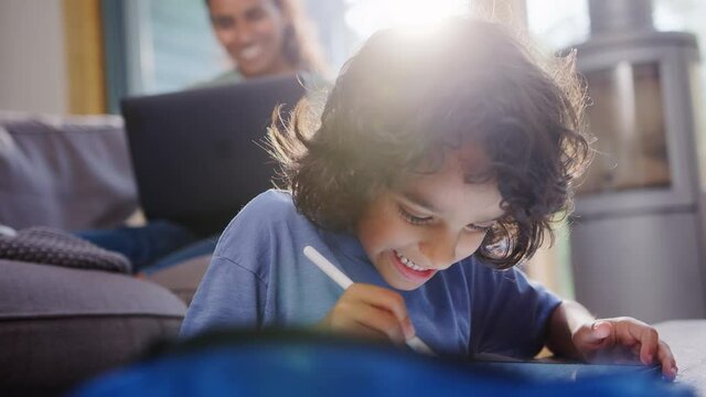 Slow motion of boy using tablet, mother working