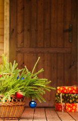 Gifts and a basket with a bouquet of fir branches are at the front door. Gift delivery concept