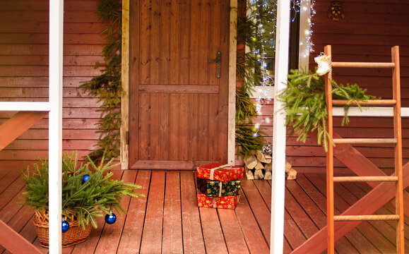 Boxes And Gifts At The Front Door Of The House, With Christmas Garlands And Wreaths