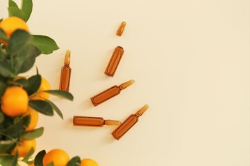 Vitamin C. Mesotherapy serum with vitamin C.Glass ampoules and tangerine fruit bushes on beige background.ampoules and Serum with Vitamin C. Organic natural cosmetics.