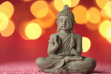 Buddha statue on red background with golden bokeh .Meditation and relaxation