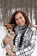 Smiling young woman in a coat with a cute puppy