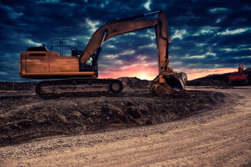 Fototapeta na wymiar Excavating machinery at the construction site, sunset in background.