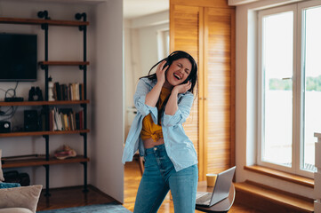 Woman dancing while listening a music on a headphones at home