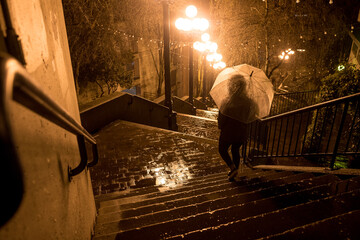 Walking with umbrella in the rain down stairs
