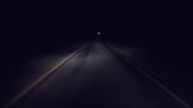 POV FPV driving in the rain at night on a dark country road passing a car