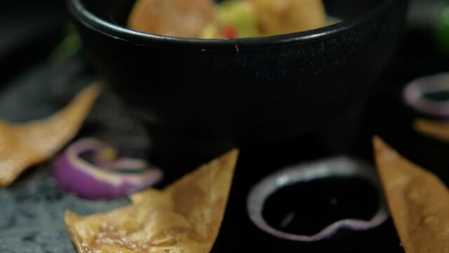 Bowl of guacamole on Mexican comal decorated with tortilla chips and vegetables