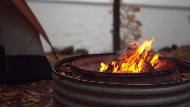 Closeup of campfire with tent in background on Fall camping trip