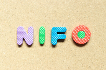 Foam alphabet letter in word NIFO (abbreviation of next in first out) on wood background
