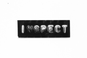 Black color banner that have embossed letter with word inspect on white paper background