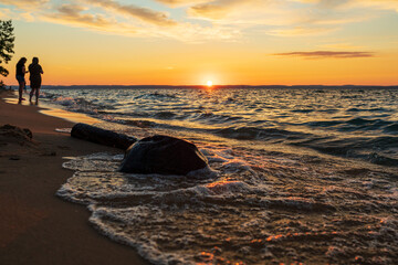 Fototapeta na wymiar People watching sunset along beach on Lake Michigan. 
