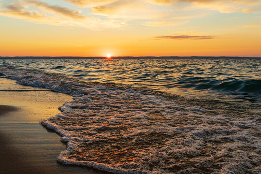 Water crashing onto Lake Michigan beach during sunset.  