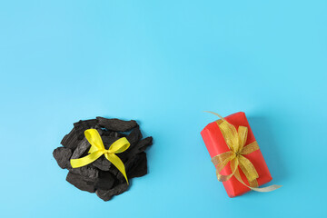 Coal with Christmas gift on color background