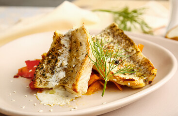 Plate with tasty baked cod fillet, vegetables and sauce on table in restaurant, closeup