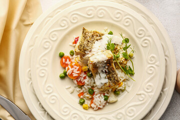 Plate with tasty baked cod fillet, rice and vegetables on light background, closeup