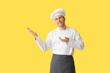 Handsome chef showing something on yellow background