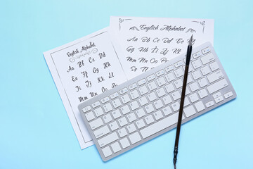 Paper sheets with alphabet, computer keyboard and brush on blue background