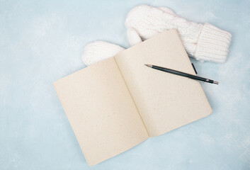 Open blank notebook wt a pencil and mittens