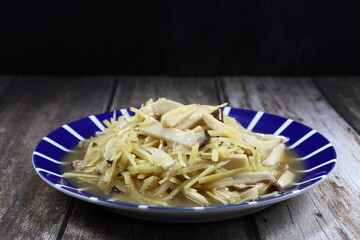 Traditional fried sliced fresh ginger with mushroom serving on the plate. Famous vegetarian food in Asia restaurant. High vitamin and nutrition menu concept. 