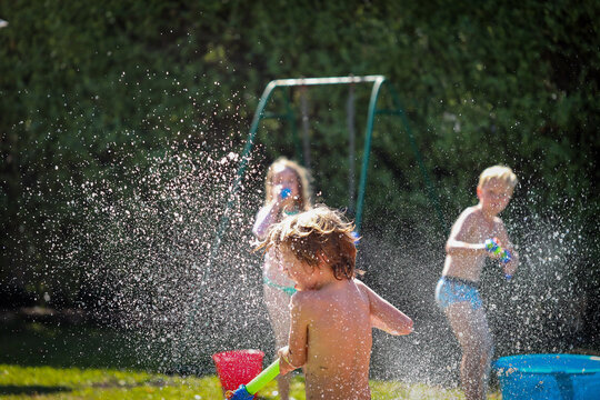 Kids Enjoying Backyard Water Fight In Summer